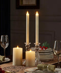Two 9-inch ivory flameless taper candles with remote and timer realistic 3D moving flame on a dining table setting.