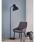 Tall Matte Black Modern Floor Lamp With Adjustable Shade for Living Room and Office next to a grey chair.
