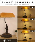 Jade Green Glass Vintage Banker Desk Lamp With Antique Brass Finish on wooden desk, showing three-way dimmable light options.