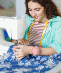 Woman using sewing machine with blue floral fabric, focus on Nine Piece Zipper Pull Replacement Kit Includes Metal Zipper Tabs For Luggage