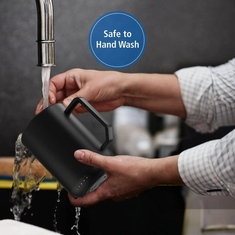 Hands holding a black stainless steel Premium Self Heating Rechargeable Coffee Mug With Precise Temperature Control under running water.