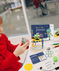 Boy in red shirt assembling Four Pack Doodling Robot Kit For Kids Ages Eight To Twelve, Bulk STEM Toys For Hands On Learning, Build Four Doodle Robots, Fun Do It Yourself Science Tech Engineering Math Projects.