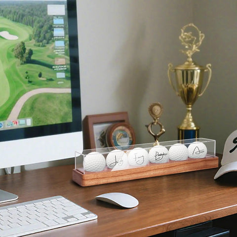 Crystal Clear UV Protected Golf Ball Display Case For Six Balls on wooden desktop with computer, trophies, and cap
