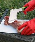 Hunters Field Dressing Kit 10 Piece Portable Game Processing Set in use, chopping meat with a cleaver on cutting board outdoors.
