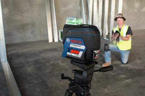 Close-up of Boss Class 12V Max Three Plane Green Beam Laser Level on tripod in construction setting with contractor.