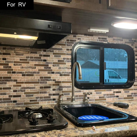 RV kitchen with black sink and gas stove, featuring thick peel and stick wall tile set for kitchen backsplash in sandstone.