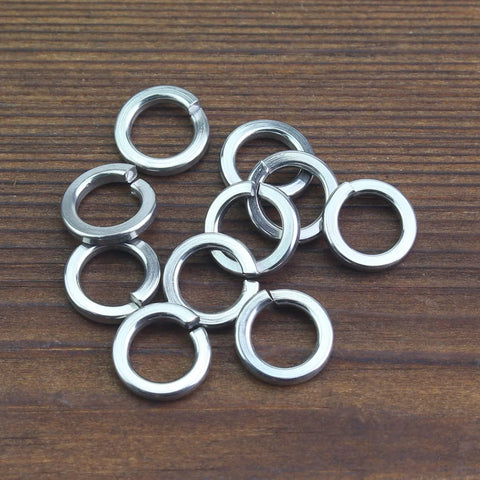 Top view of about a dozen M4 stainless steel split lock washers, silver on wood surface