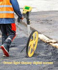 Roll Out Precision Digital Measuring Wheel With Bright Backlit LCD Display And Telescoping Handle on job site with asphalt background.