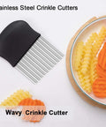 Stainless steel crinkle cutter with black non-slip handle; side view beside sliced vegetables
