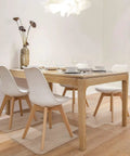 Dining room with white chairs, wooden table set on hardwood floor with chair mats protecting the surface.
