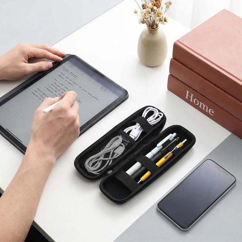 Heavy Duty EVA Hard Shell Pencil Case For Your Daily Grind keeps pens and cables organized on a desk next to a tablet.