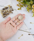 Hand holding Arrowhead Charms 60Pcs Set in gold, silver, bronze with coin for size comparison, showcasing three color Tibetan style alloy charms.