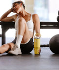 Heavy Duty 30 Oz Vacuum Insulated Tumbler With Flip Straw Lid placed next to a resting athlete in a gym setting.