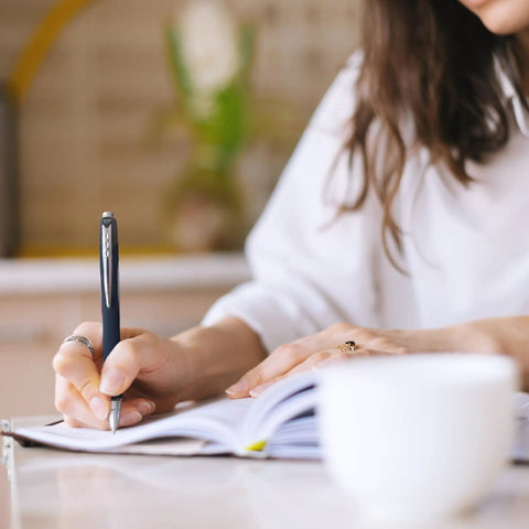 Person writing in a notebook with Super Smooth Hybrid Ink Ballpoint Pens with Black 0.7 Mm Fine Point Tips Pack of 3.