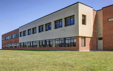 Slim Outdoor LED Wall Pack Light with Dusk To Dawn Sensor illuminating a modern brick building exterior in daylight.