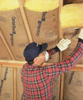 Worker installing Heavy Hitter R 38 Fiberglass Insulation Bats 8 Bundle Pack 24 By 48 Inch in attic for thermal resistance.