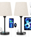 Set Of 2 Dimmable Touch Bedside Lamps With USB C And AC Outlet Charging Station next to charging phone, tablet, and smartwatch