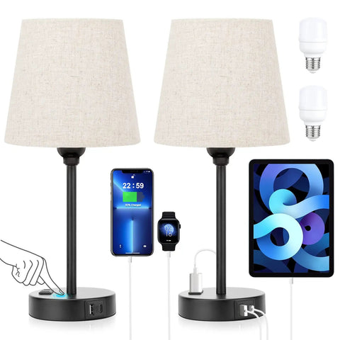 Set Of 2 Dimmable Touch Bedside Lamps With USB C And AC Outlet Charging Station next to charging phone, tablet, and smartwatch