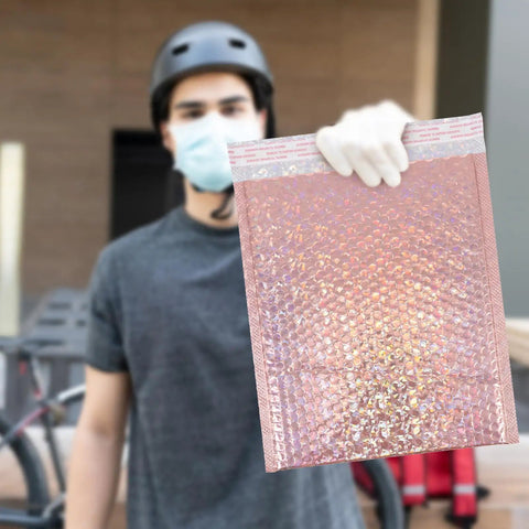 Person holding a Rose Pink Holographic Padded Mailers 25x30cm Self Seal Waterproof Shipping Bags 10 Pack, protective bubble envelope