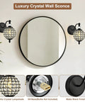 Lumestary 1 Piece Black Crystal Globe Wall Sconce, 1-Light Matte Black Finish Wall Sconce for Bathroom Bedroom Living Room, Vintage Vanity Light beside a round mirror.