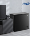 Top Shelf 7.0 Cu Ft Chest Freezer In Black With A Nifty Basket And No Sweat Defrost Drain positioned near a TV stand.
