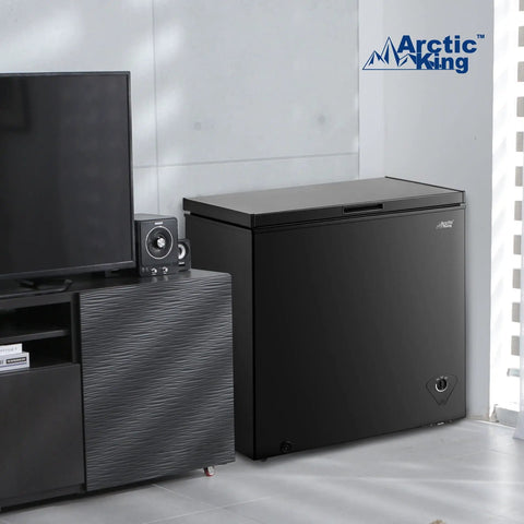 Top Shelf 7.0 Cu Ft Chest Freezer In Black With A Nifty Basket And No Sweat Defrost Drain positioned near a TV stand.