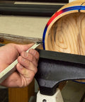 Woodturning tool, 12-inch stainless steel, 90° carbide, unhandled, held by hand at a wood lathe with a round wooden blank.