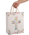 13 Inch Large Light Yellow Floral Gift Bag Set With Greeting Card And Tissue Paper For First Communions Baby Girl Baptisms Christenings And Religious Occasions One Piece, showing floral cross motif held by hand