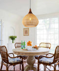 Hand Woven Rattan Pendant Light With Sturdy Wood Frame, 15 Inch Boho Ceiling Fixture For Kitchen Island And Dining Room hanging over a wooden dining table.