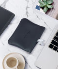 Smooth Vintage Black Leather Squeeze Coin Purse With Heavy Duty Spring Frame, Super Compact Change Holder And Cash Pocket For Hassle Free Everyday Carry By Men And Women on marble surface.
