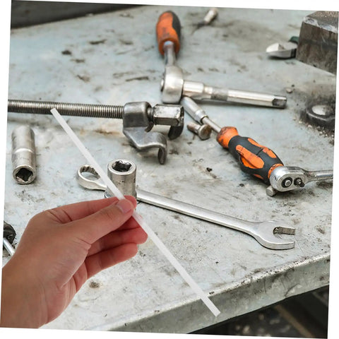 Hand holding a white rod with tools around, showcasing the 10 Pcs Car Bumper Welding Rods for Quick Bumper Repairs, DIY friendly.
