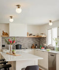 Milk Glass Globe Semi Flush Mount Ceiling Light With Gold Brass Finish in modern kitchen setting above countertop.