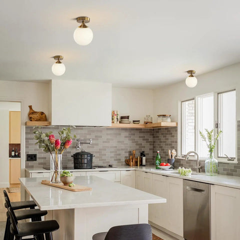Milk Glass Globe Semi Flush Mount Ceiling Light With Gold Brass Finish in modern kitchen setting above countertop.