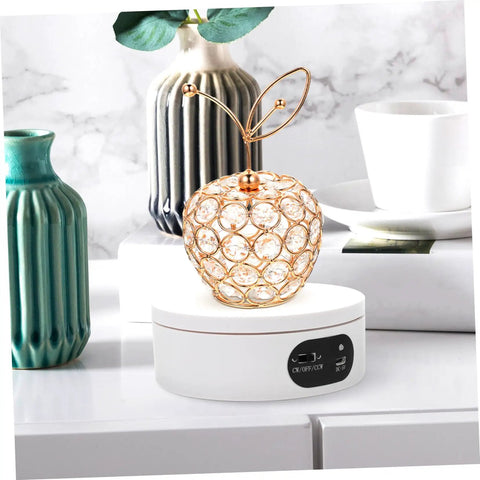 Rotatable Jewelry Display Stand With Electric Motorized Turntable Skid Base showcasing a crystal apple design on a white base.