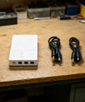 Keep The Wifi Alive With This Solid 7800mAh UPS Battery Backup, showing the unit and two DC output cables on a workbench.