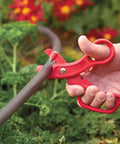 Premium Drip Irrigation Tubing Cutter And Hole Punch Tool Kit Two Pack With Comfy Grip cutting a poly tube in a garden.