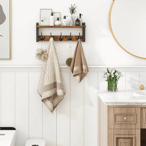 Rustic Wood Wall Shelf With Five Metal Hooks Coat Rack For Your Entryway Hallway Bathroom Mudroom And Bedroom Keeps Hats Coats Purses Towels Sorted And Chic In Rustic Brown And Black Finish mounted on a white bathroom wall with towels hanging.