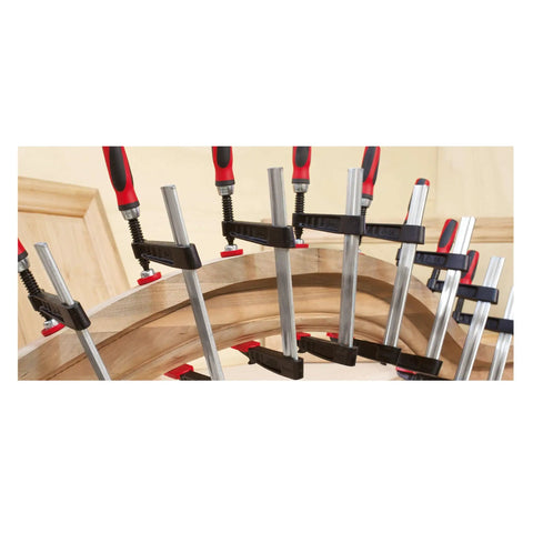 Tradesman Clamp With Four Inch Throat Depth And Twelve Inch Reach In Black And Red Heavy Duty Woodworking Clamp With Patented Serrated Rails For Anti Slip Grip And Buckle Free Lock Ergonomic Wooden Handles Made In USA clamping curved wood panel