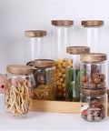 Straight Up Solid Airtight Coffee And Tea Storage Canister With Smooth Wood Lid showcasing multiple clear glass jars with snacks.