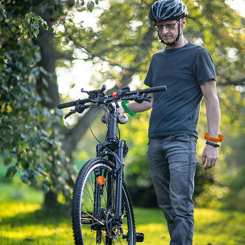 Man wearing 24 Piece Bicycle Theme Motivational Silicone Wristbands Set For Parties BMX Vibes Rubber Wristbands posing with bicycle.