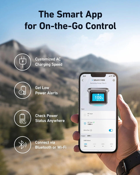 Hand holding smartphone displaying SOLIX C1000 Portable Power Station app interface in outdoor setting with mountains in background