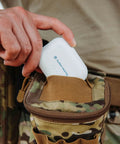 Ion Pro 2 Bluetooth Rechargeable OTC Hearing Aids case being placed in a camouflage pouch by a person.