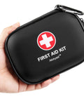 Hand holding Mini First Aid Kit 120 Piece Waterproof Hard Shell Medical Kit for Car Home Office Travel Camping Sports Outdoors and School Grab And Go Emergency First Aid Supplies And Survival Kit In Compact Portable Case Black.