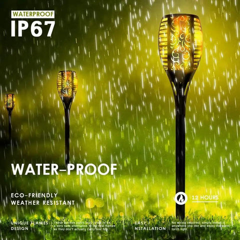 Four Pack Outdoor Solar Torch Lights With Lit Flickering Flame 33 LED Waterproof Tiki Torches For Garden Patio And Pathway Decor Auto On Off Energy Efficient Solar Powered At Dusk And Dawn Weatherproof All Weather Build For Outdoor Use shown in rain.