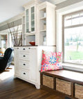 Bright living room with cabinets, a colorful pillow on a bench, and large windows offering a scenic view.