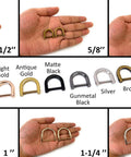 Assorted metal D rings in various sizes and finishes displayed on a hand for comparison.