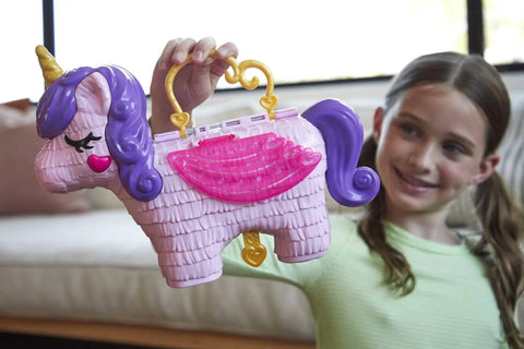 Girl holding Unicorn Party Playset With 25 Surprises, Pink Unicorn Toy With Purple Hair, Confetti Pinata Fun, Castle Adventure