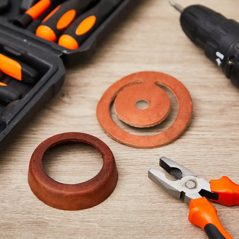 Two Set Leather Pitcher Pump Repair Kit with leather lower valves and cups next to installation tools on a wooden surface