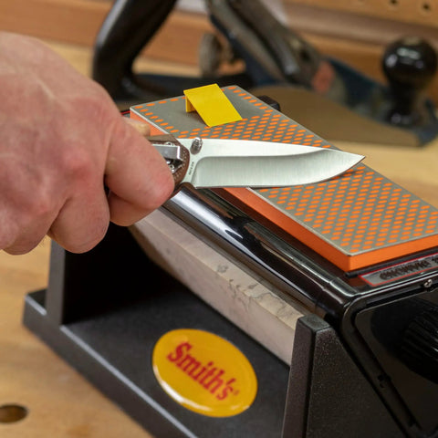 Person sharpening knife on Diamond Tri-Hone Bench Stone Set 8 Inch With Coarse Fine And Natural Arkansas Stones Three Way Honing System