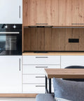 Modern kitchen with matte black stainless steel cabinet handles set on wood and white cabinetry.